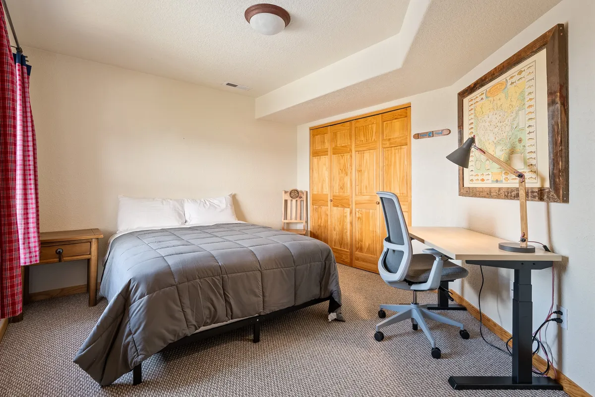 A tranquil bedroom with a bed, dedicated work desk, chair, map artwork, and wardrobe. The space is peaceful and functional, ideal for guests who need to work remotely or enjoy a quiet, restful environment.
