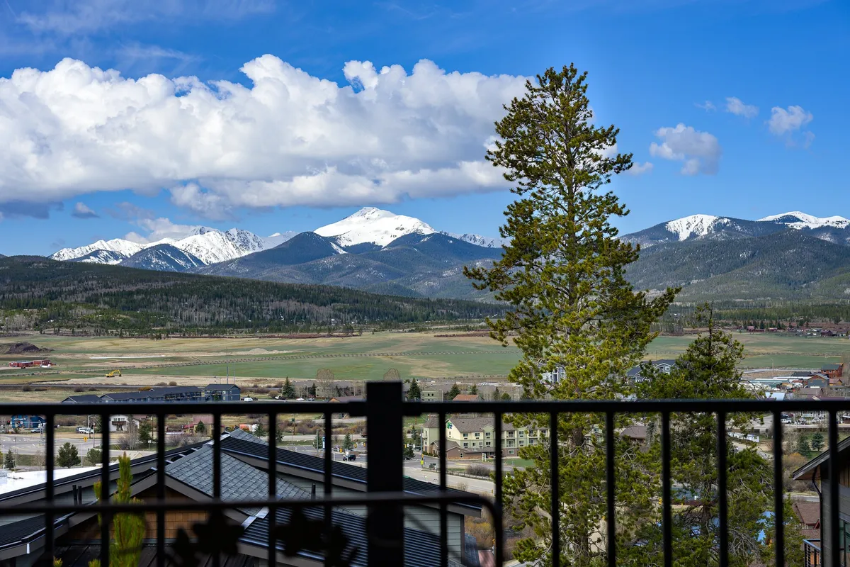 A sweeping view of a mountain range under a dramatic sky, with a lone tree in the foreground. The scene evokes the wide open spaces and natural beauty surrounding the area, offering hints of hiking and outdoor relaxation opportunities.